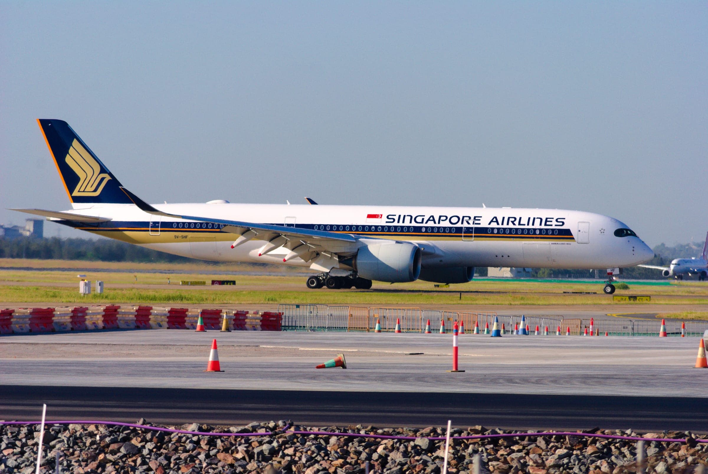 A Singapore Airlines Airbus A350-900 on the runway at Brisbane, seen side-on across the airfield.