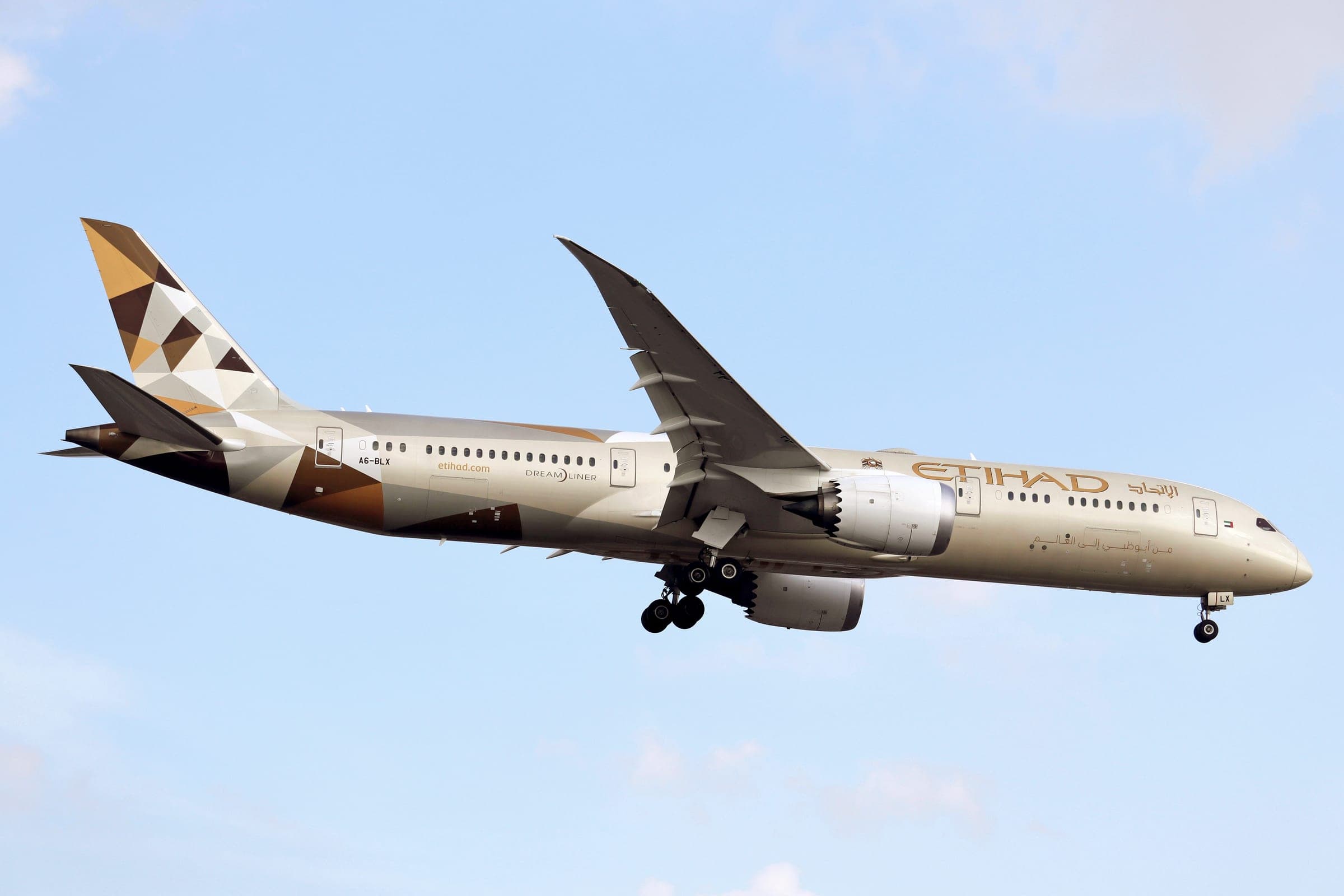 An Etihad Airways Boeing 787-9 Dreamliner, registration A6-BLX, on approach at Toronto Pearson with its landing gear down, in the airline's sand-coloured livery with a geometric tail.