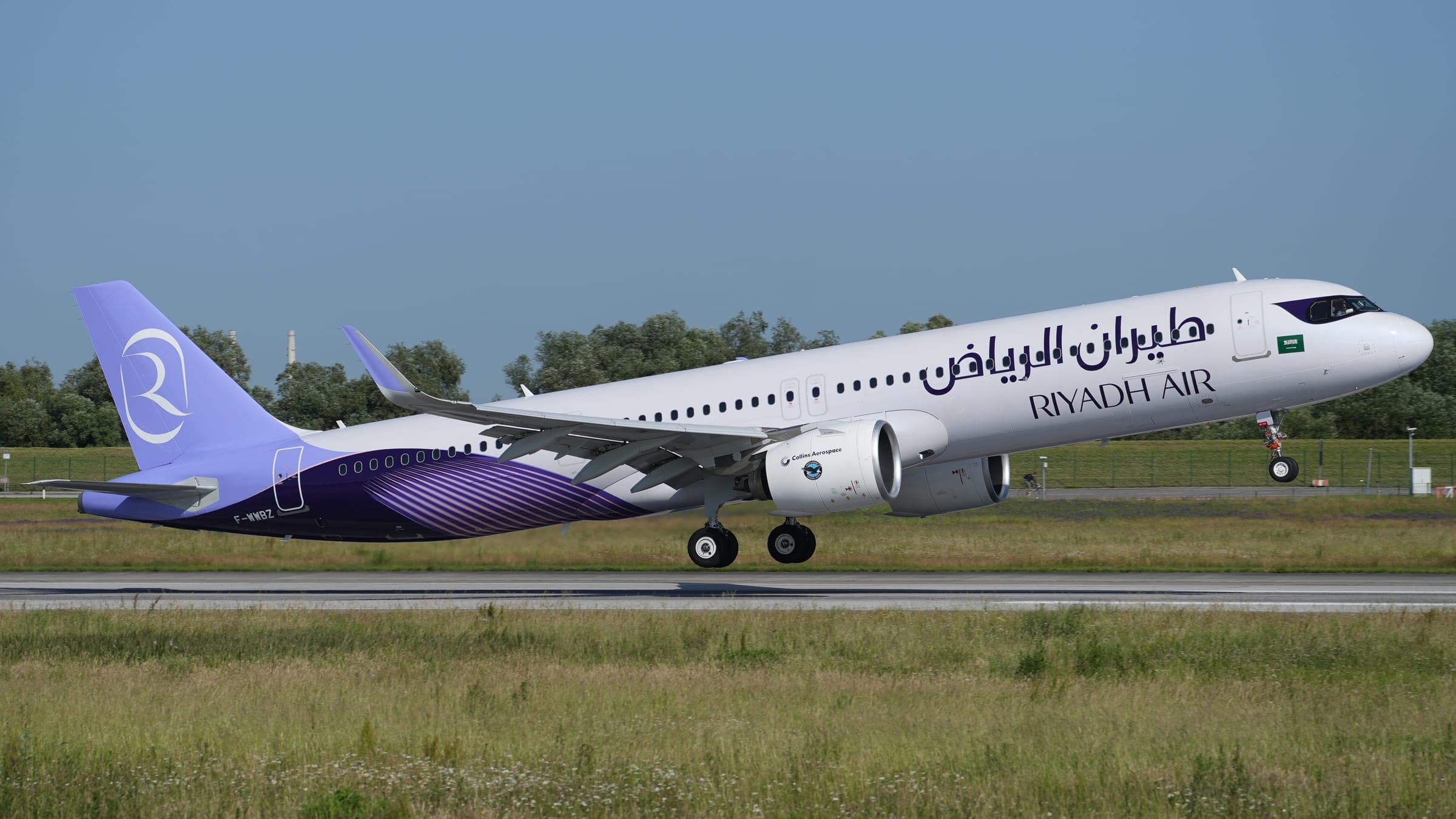 An Airbus A321neo XLR prototype painted in Riyadh Air livery, white with a lavender and purple tail and Arabic and English titles, lifting off from the runway at Hamburg-Finkenwerder.