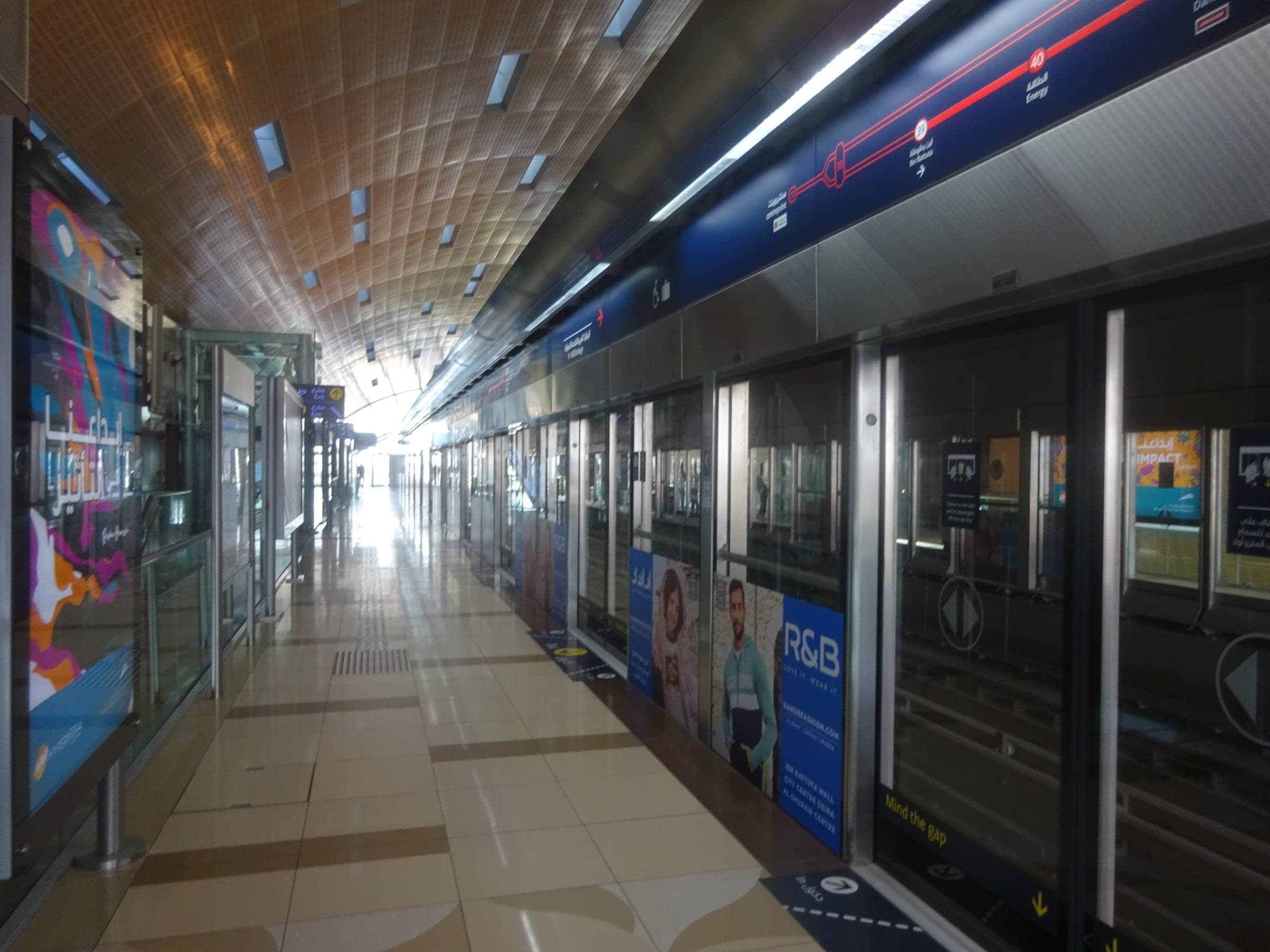 A Dubai Metro platform with the train doors open and the station's curved ceiling above.